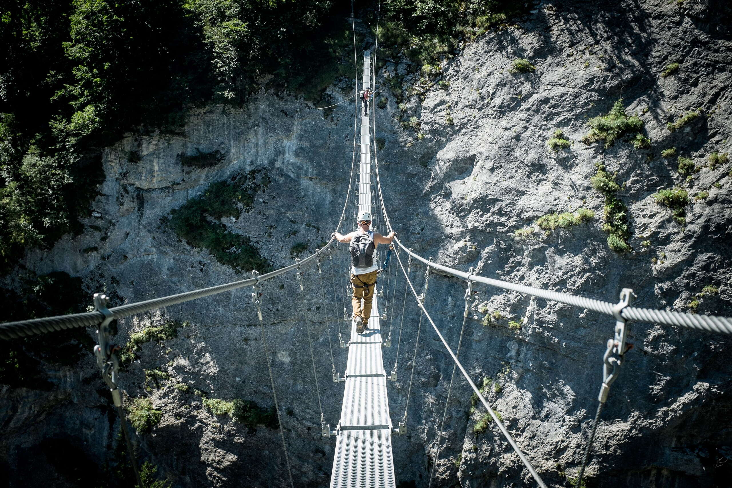 Auf dem Klettersteig Mürren überquert ein Kletterer die Hängebrücke richtung Gimmelwald. Der Klettersteig in Mürren bietet Adneralin pur.